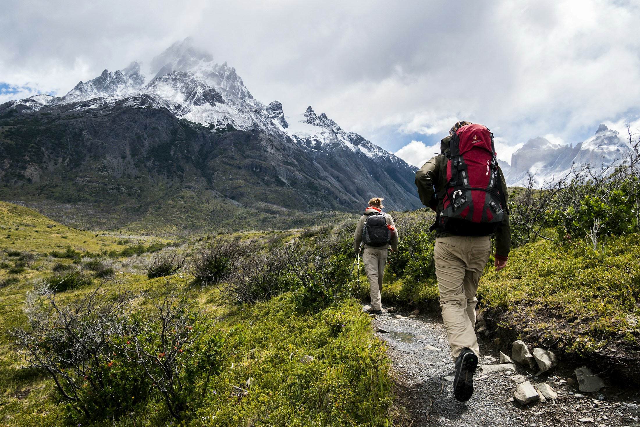 Hikers following a trail through a sunlit mountain landscape
